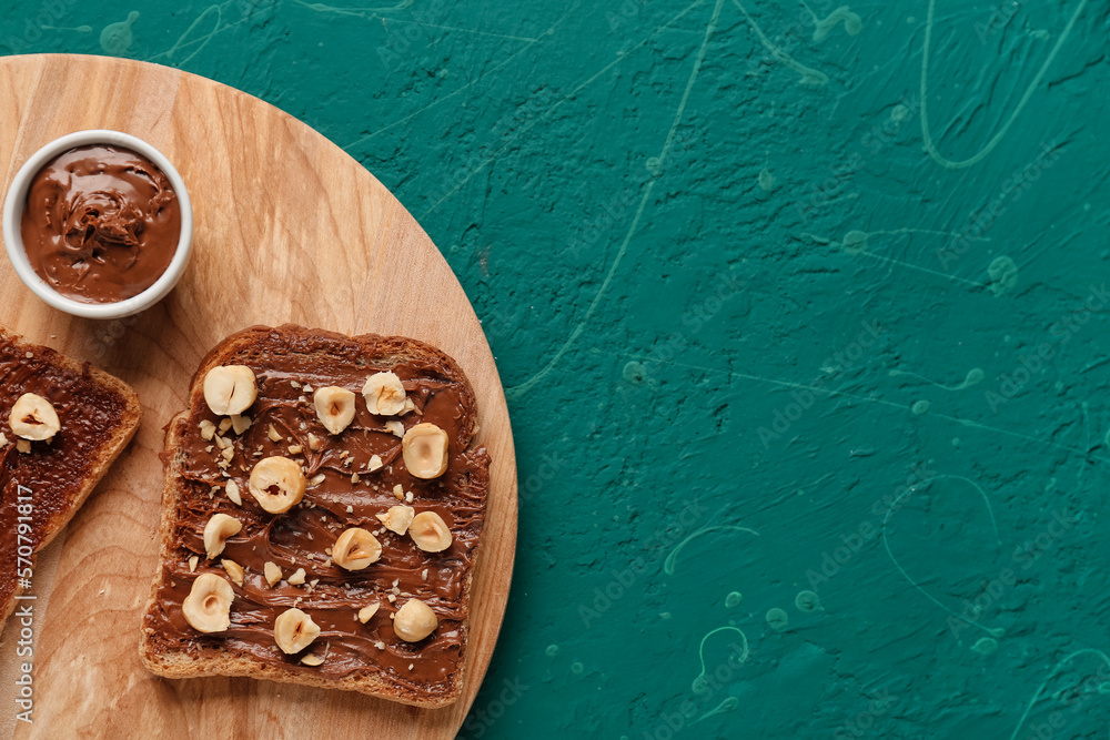 Wooden board of tasty toasts with hazelnut butter and nuts on color background