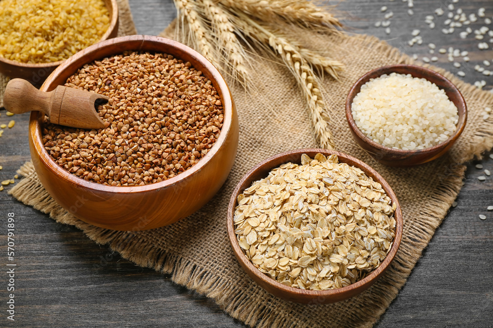 Bowls of different cereals on dark wooden background