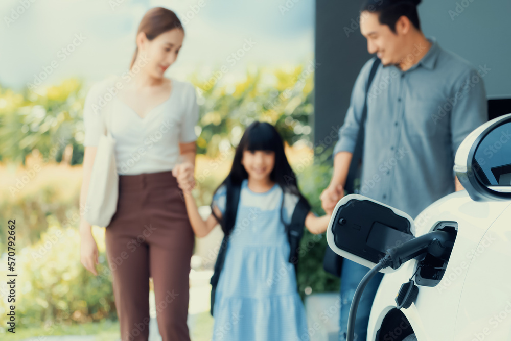 Focus closeup electric vehicle recharging battery from home electric charging station with blurred f