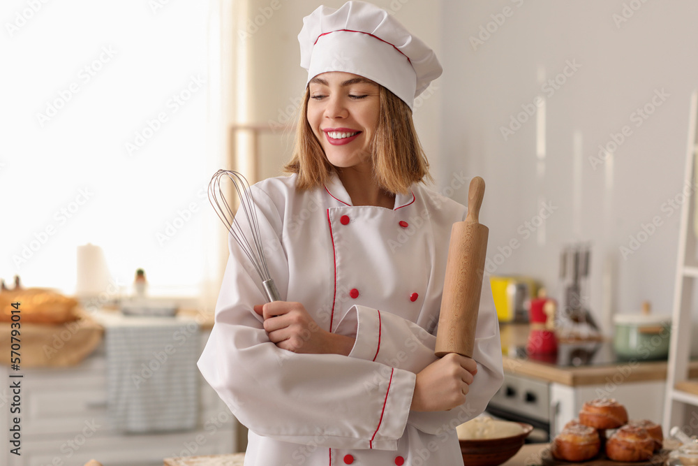 Female baker with rolling pin and whisk in kitchen