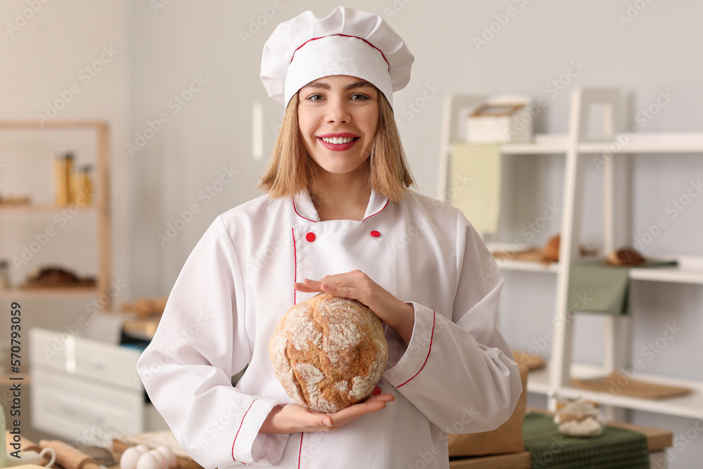 Female baker with fresh bread in kitchen