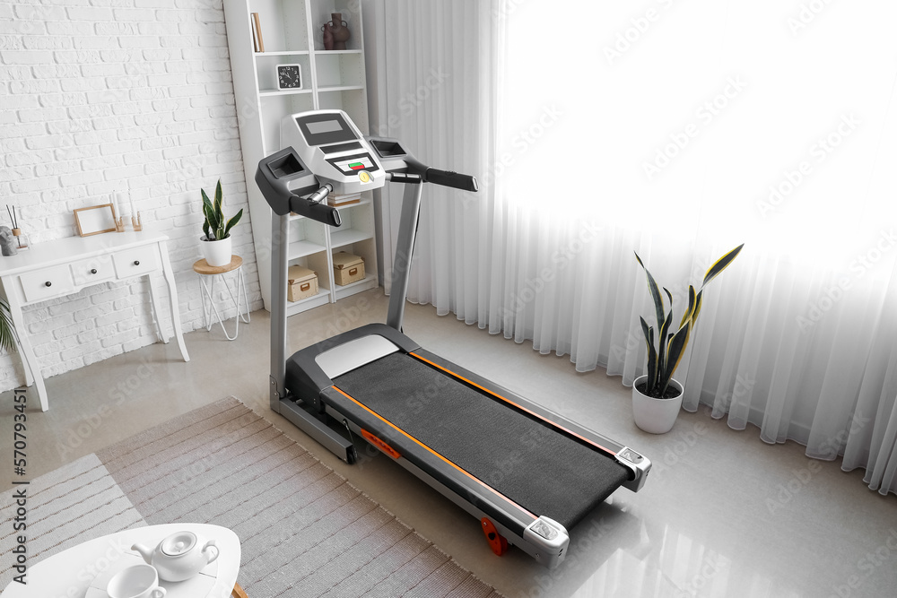 Interior of living room with modern treadmill near window