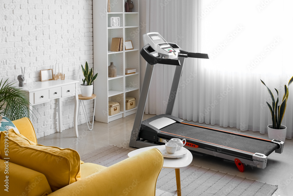 Interior of living room with modern treadmill near window