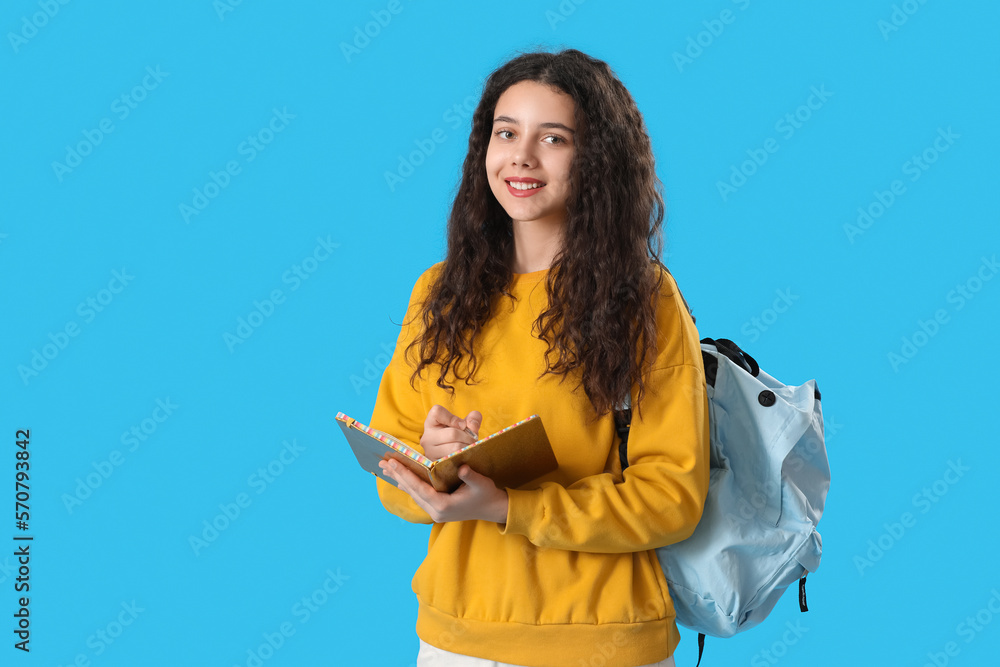 Female student with notebook and backpack on blue background