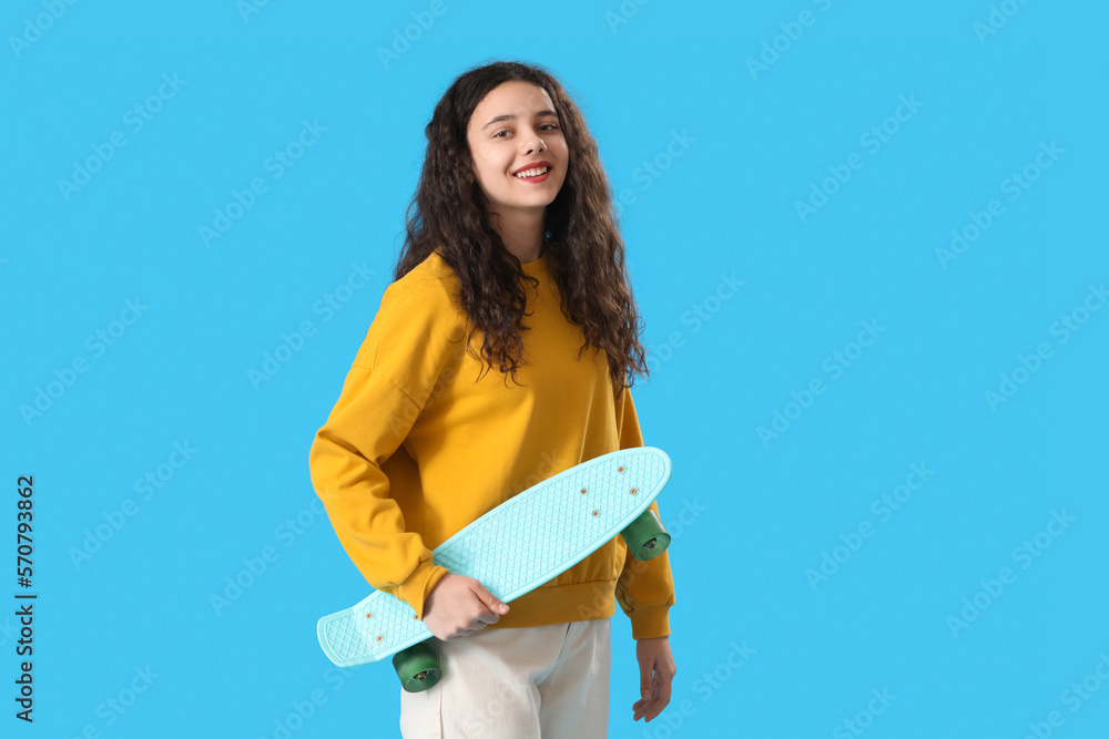 Teenage girl with skateboard on blue background