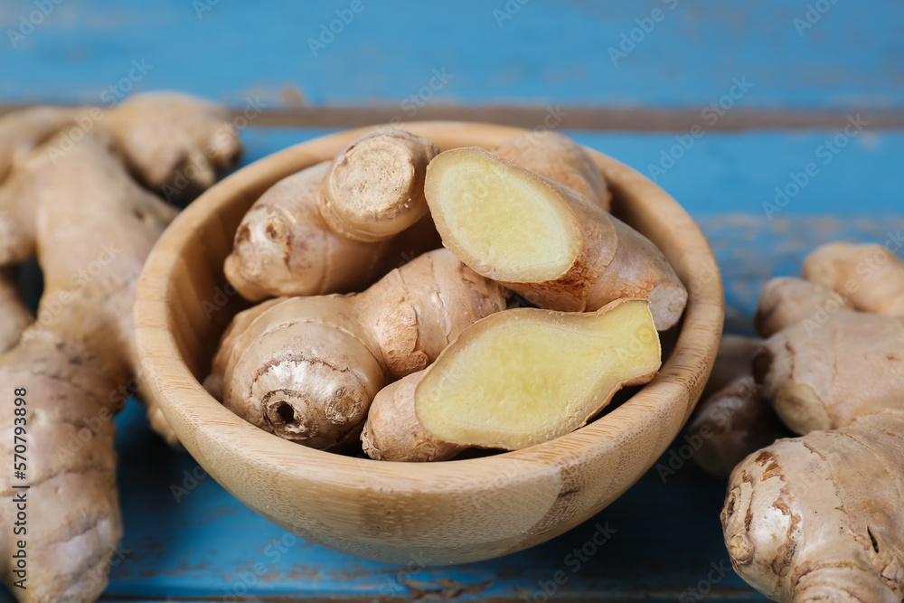 Bowl with ginger roots on blue wooden background