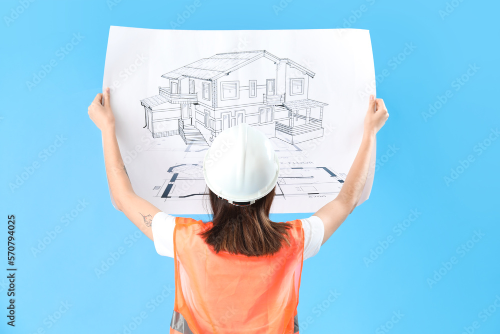 Female engineer with drawing on blue background, back view