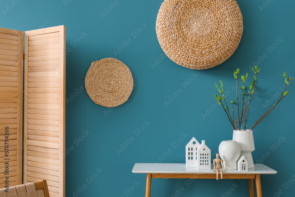 House candle holders, wooden mannequin and houseplant on table near blue wall