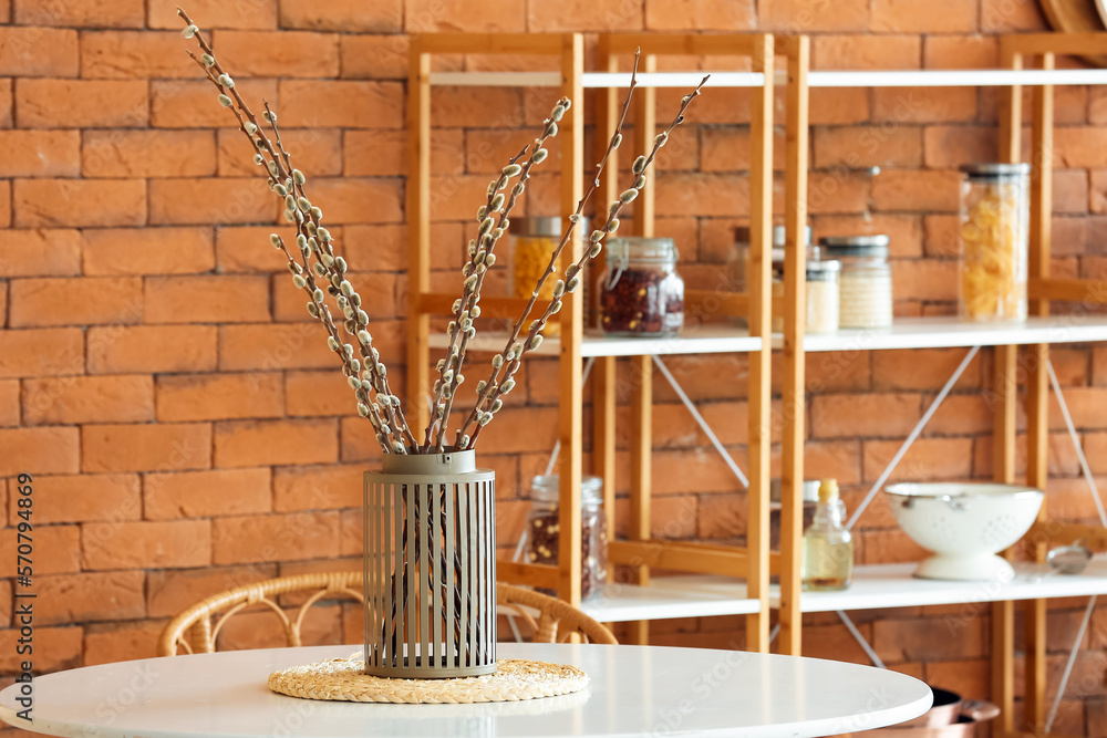 Vase with willow branches on dining table in kitchen