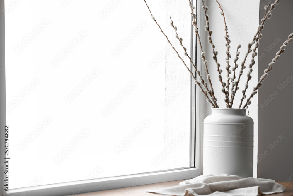 Vase with pussy willow branches on windowsill in room