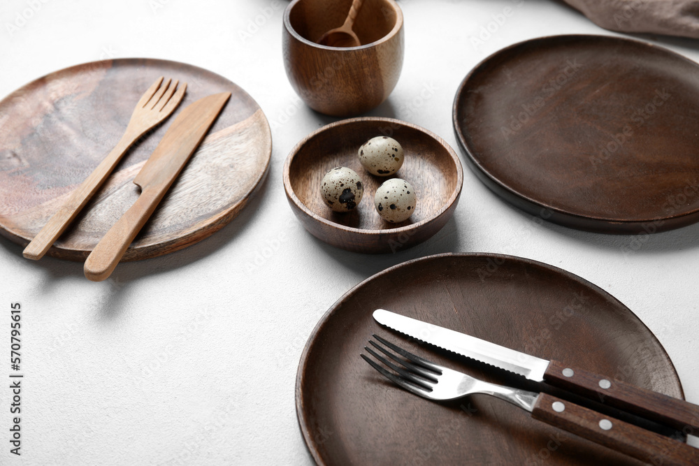 Beautiful table setting with wooden plates and quail eggs on white background, closeup