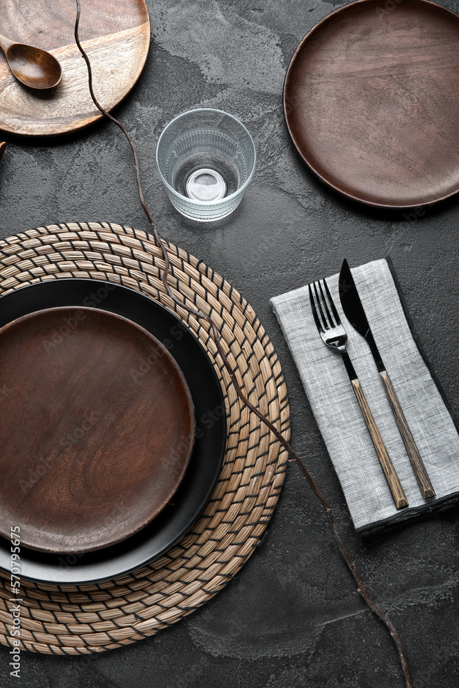 Beautiful table setting with wooden plates and tree branch on dark background