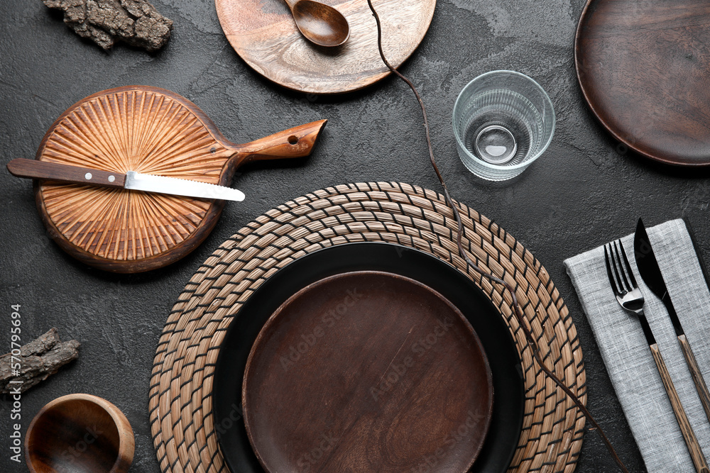 Beautiful table setting with wooden plates and tree branch on dark background