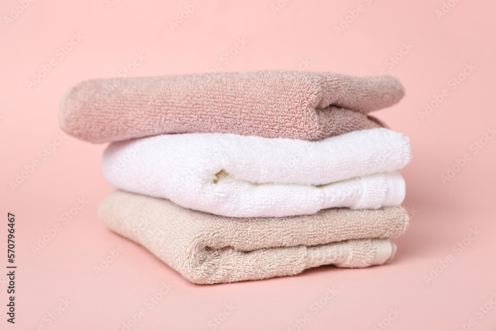 Stack of clean towels on pink background