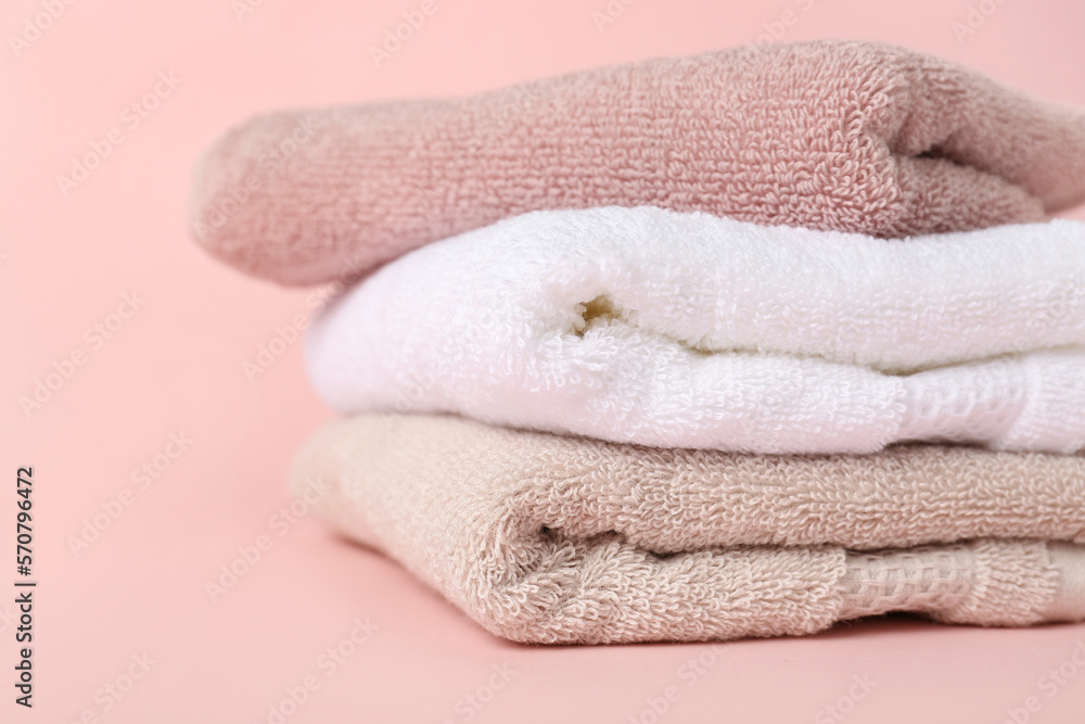 Stack of clean towels on pink background, closeup