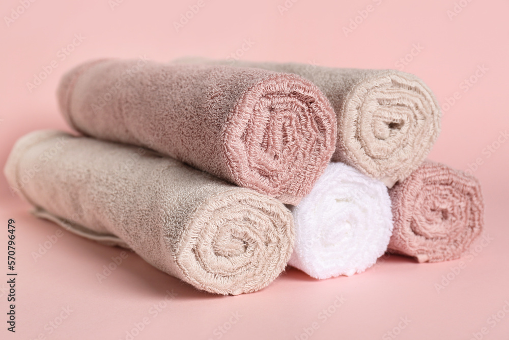 Rolled clean towels on pink background