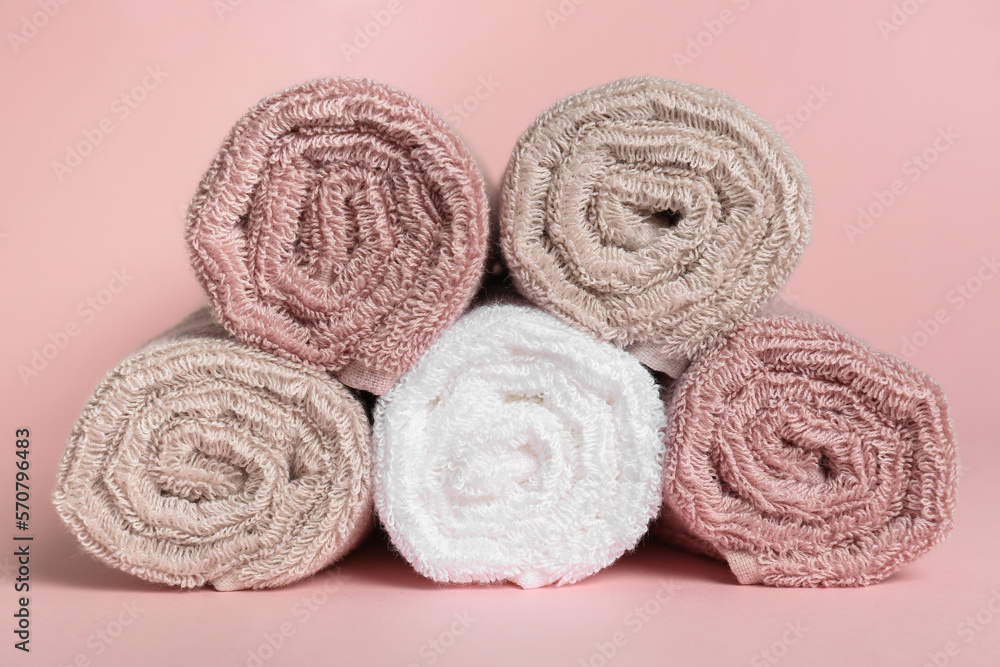 Rolled clean towels on pink background