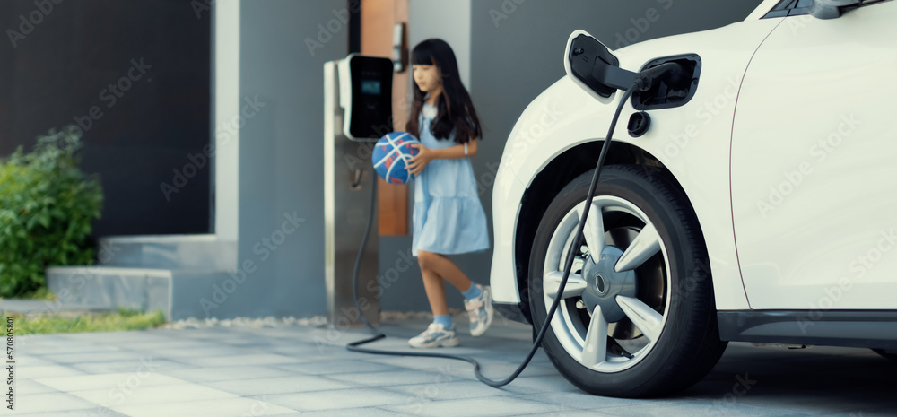 A playful and happy girl playing around at her home charging station providing a sustainable power s