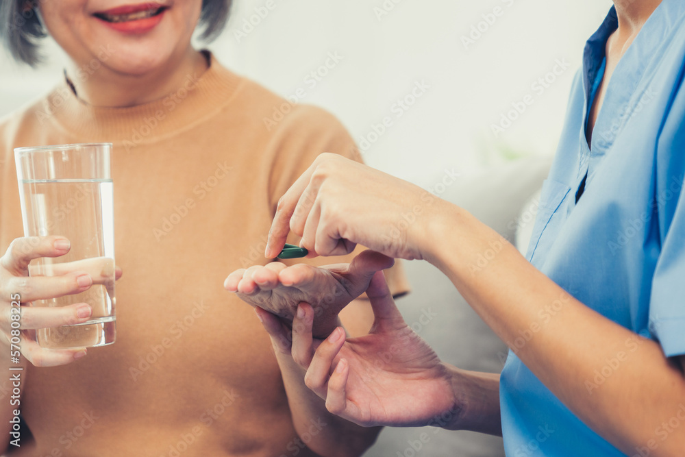 Contented senior woman taking medicines while her caregiver advising her medication. Medication for 