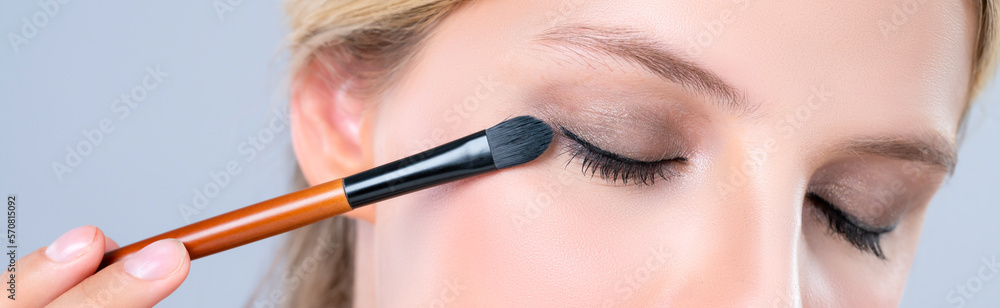 Closeup beautiful girl with flawless applying alluring eye shadow makeup with eyeliner brush. Cosmet