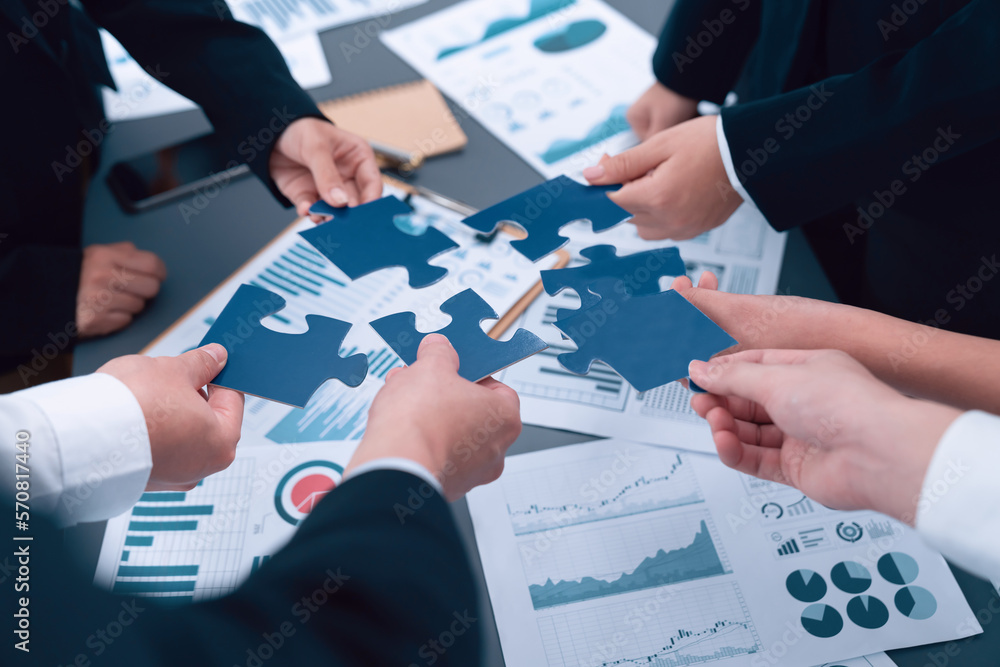 Closeup top view business team of office worker putting jigsaw puzzle together over table filled wit