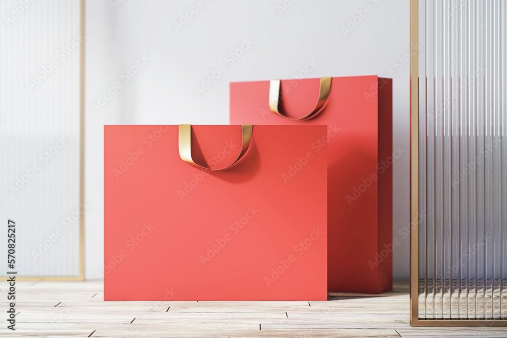 Front view on blank red paper shopping bags with place for your brand name or text on light wooden f