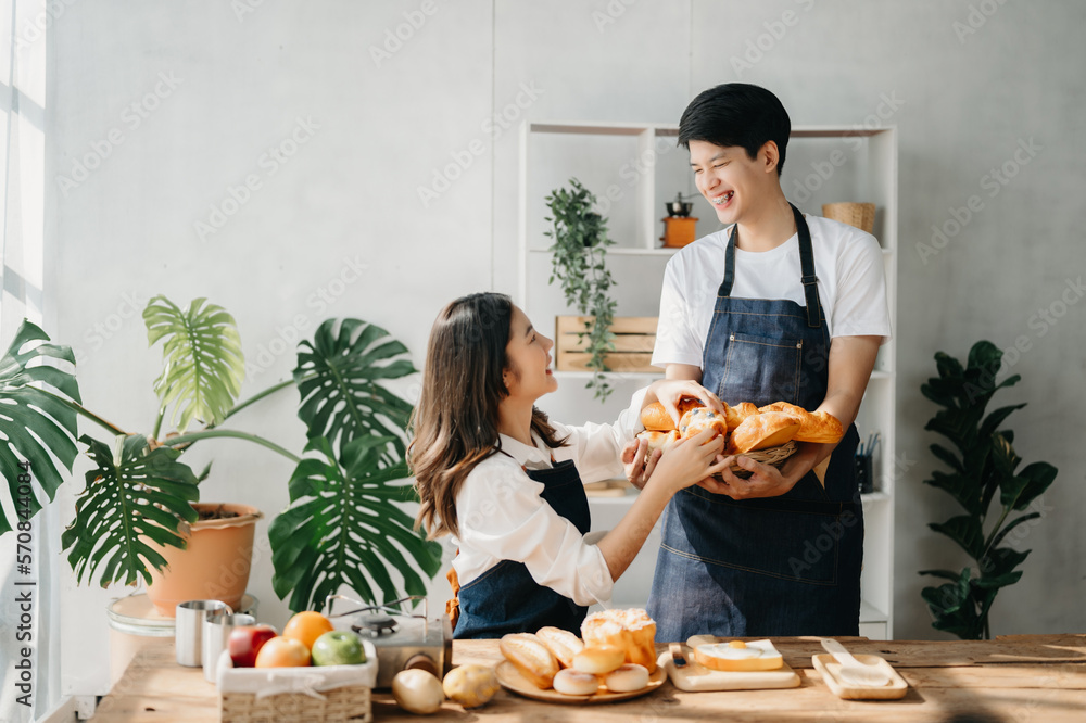 A man in the kitchen preparing a meal with Bread and fruit in cozy kitchen while his wife hugging hi