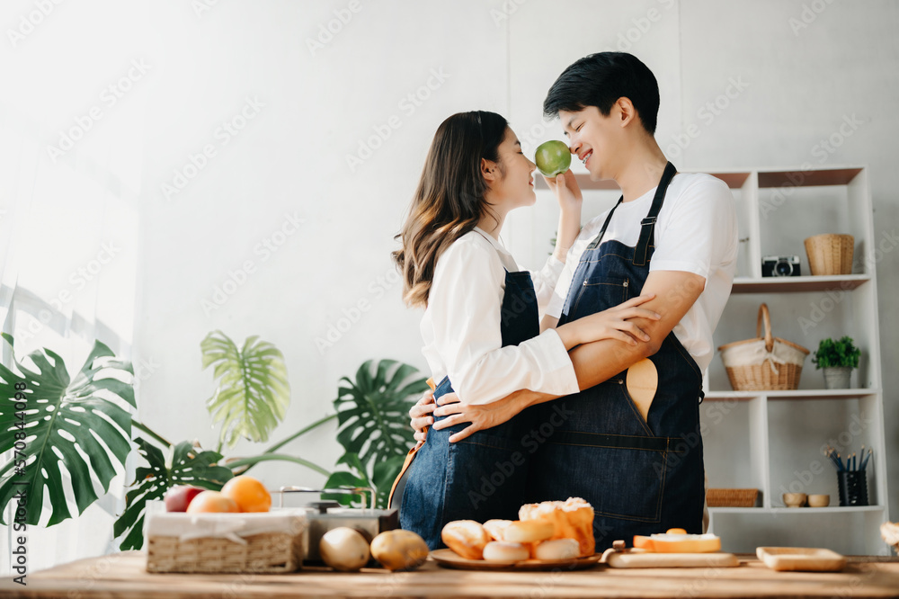 A man in the kitchen preparing a meal with Bread and fruit in cozy kitchen while his wife hugging hi