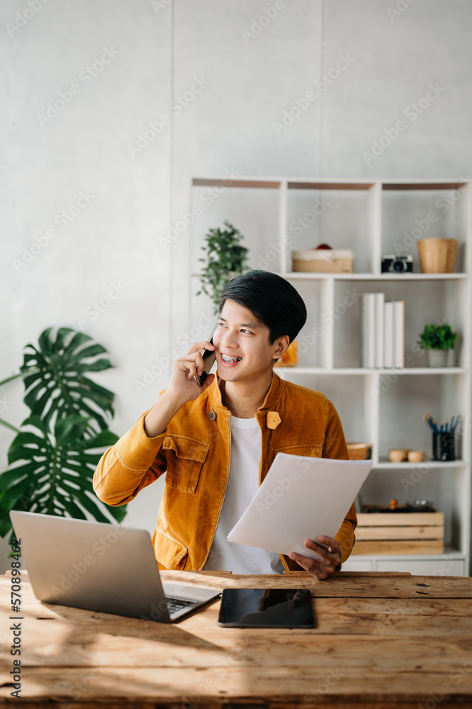 Happy asian business man have the joy of talking on the smartphone, tablet and laptopon the home off