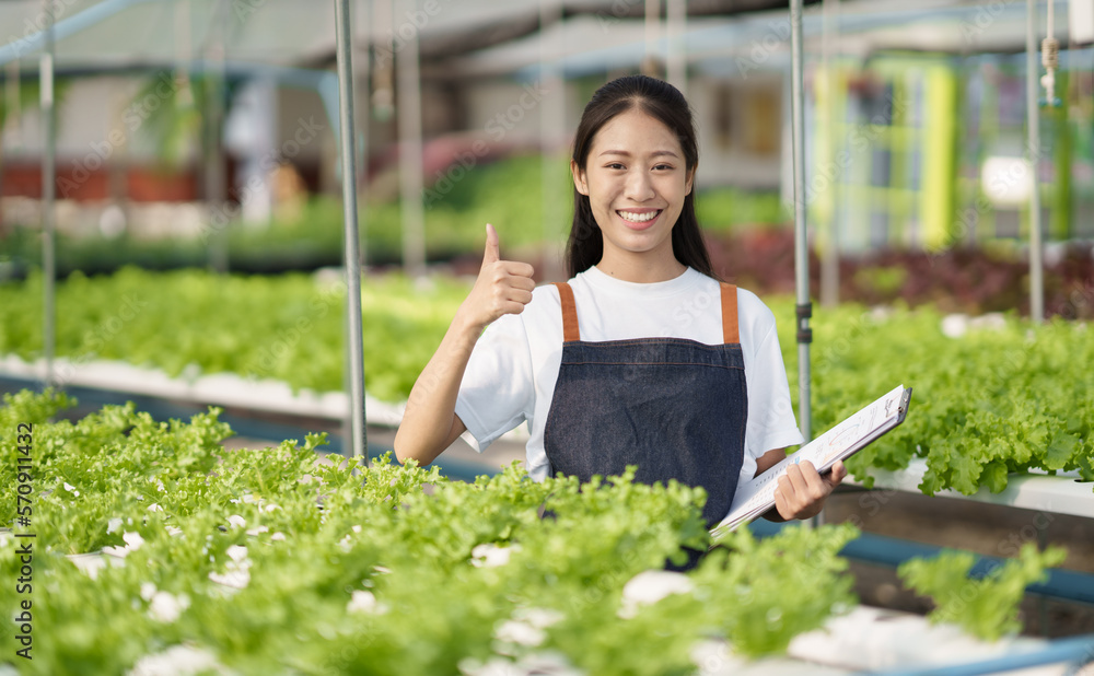 Portrait of young Asian farm worker standing in the salad farm with the thumbs up hand.