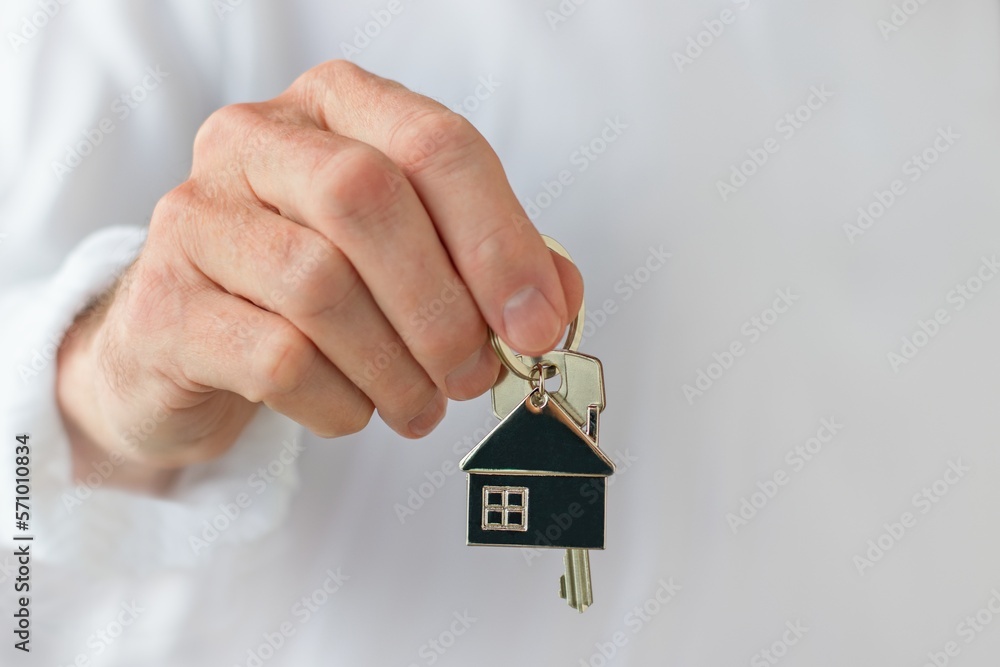 Mans hand holding a house key. Concept of buying a new house or home.