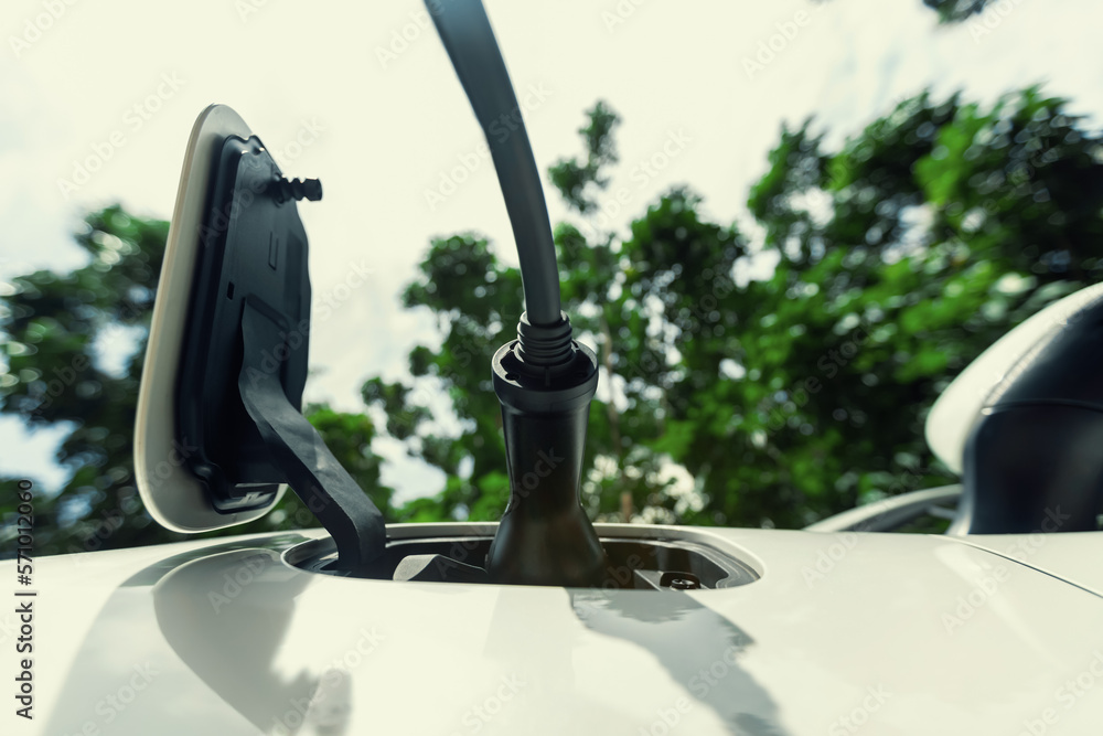 Closeup EV charger plugged into electric vehicle socket at charging station image from below view as