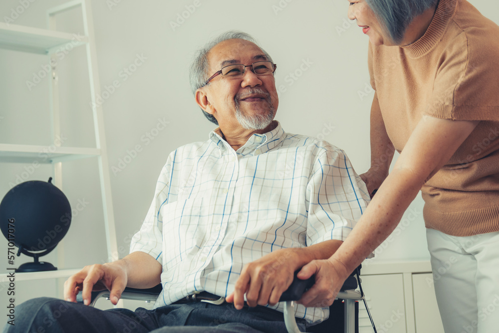 Senior wife giving support to her husband in his wheelchair with love, contented pensioner life. A s