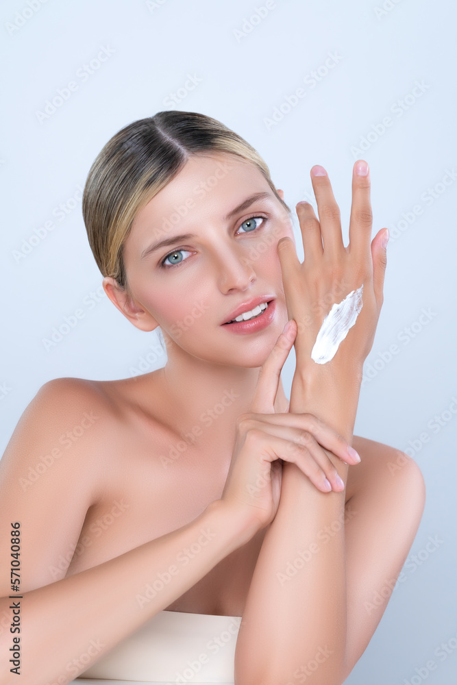 Alluring beautiful woman applying moisturizer cream on her hand for perfect skincare treatment in is