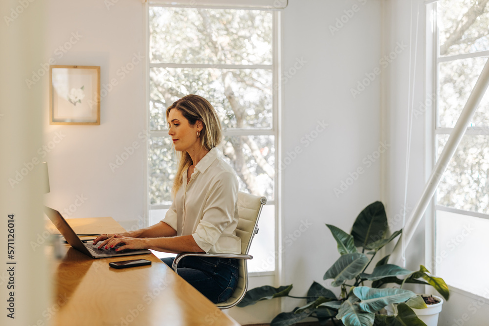 Creative businesswoman typing on a laptop in her office