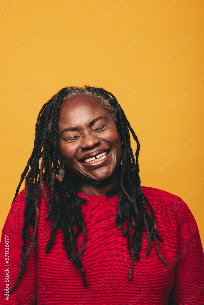 Middle-aged woman with dreadlocks laughing cheerfully in a studio