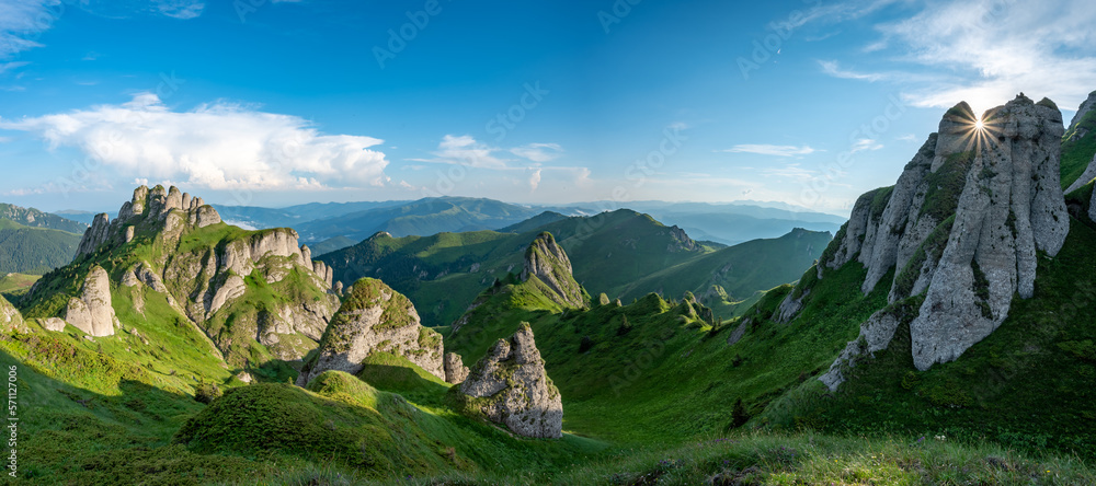 Panorama of green meadow with rocks and rocky mountains in romanian mountains in muntii ciucas with 