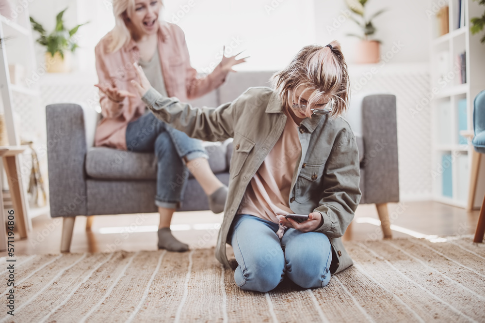 Mother arguing with her daughter chatting on smartphone.