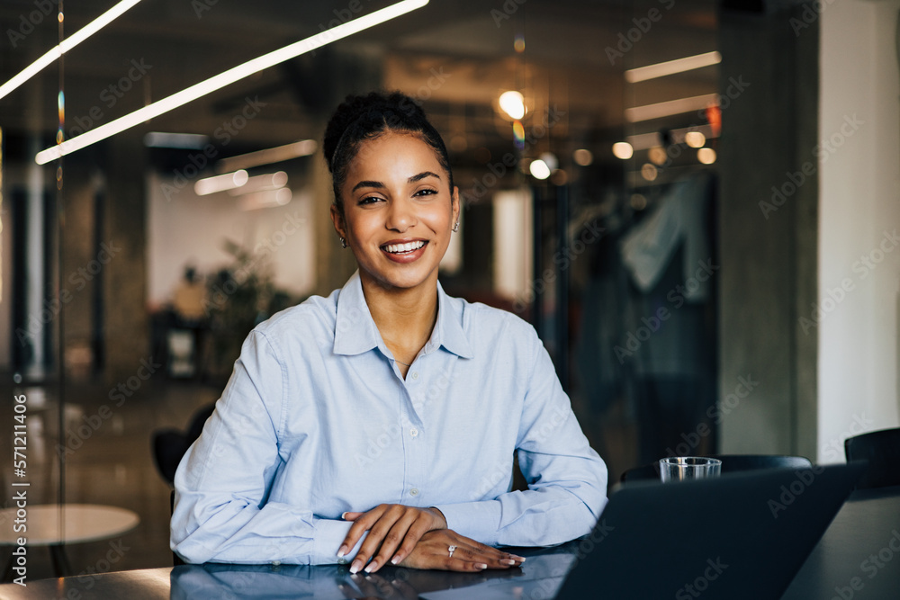 Happy African businesswoman sitting at the office, posing for the camera.