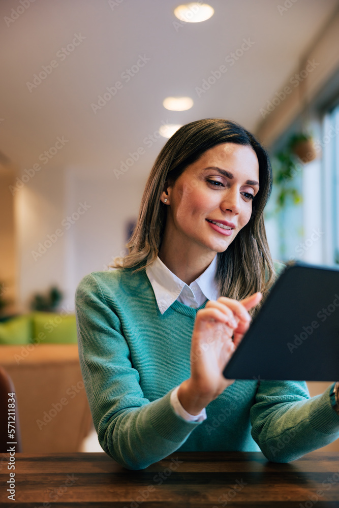 Businesswoman typing on digital tablet, sitting at the workplace.