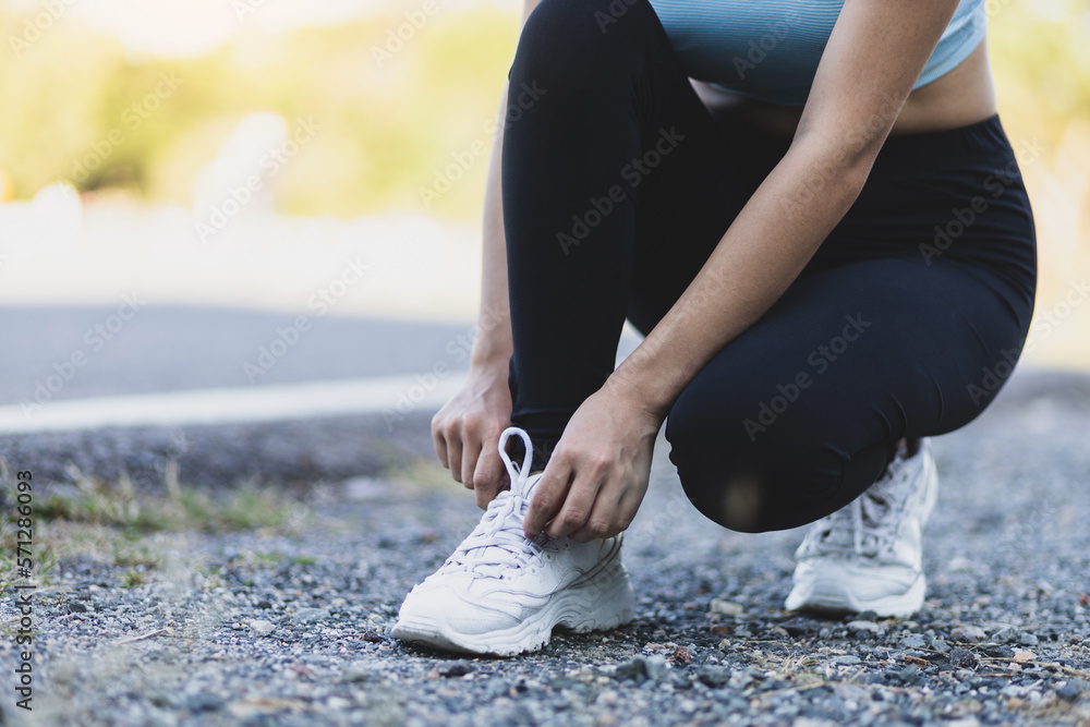 Woman running athlete tying shoelaces. Get ready to start exercising or running. Healthy lifestyle c