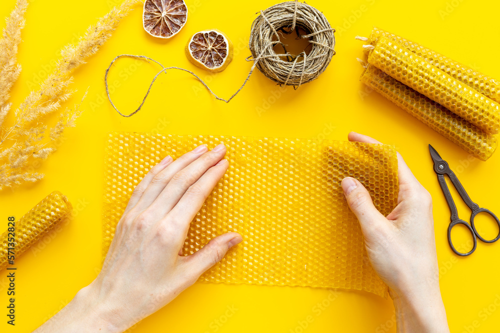 Hands making beeswax honey aroma candles with honeycombs, top view