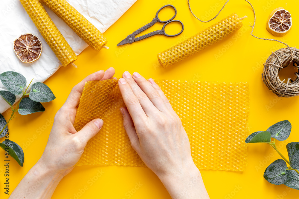 Hands making beeswax honey aroma candles with honeycombs, top view