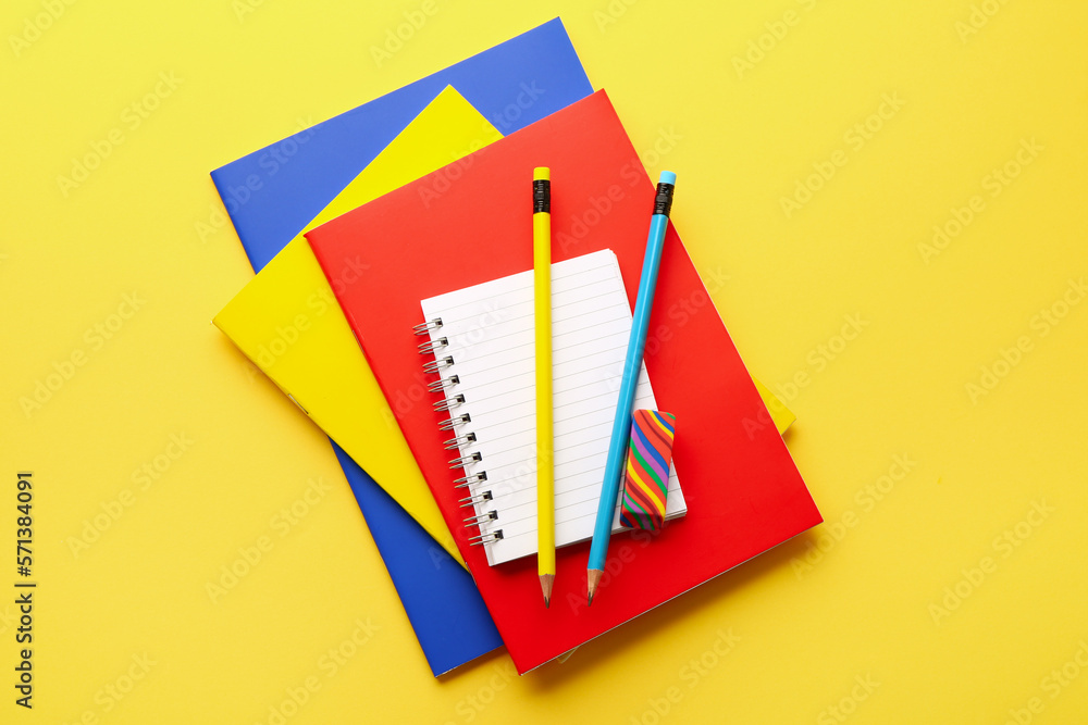 Notebooks, pencils and eraser on yellow background