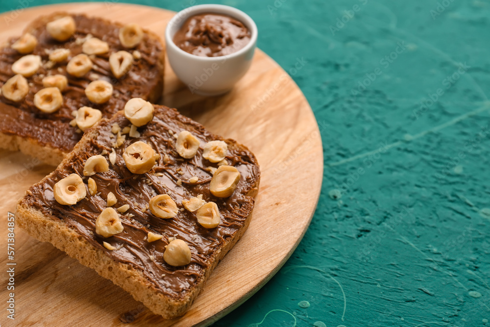 Wooden board of tasty toasts with hazelnut butter and nuts on color background, closeup