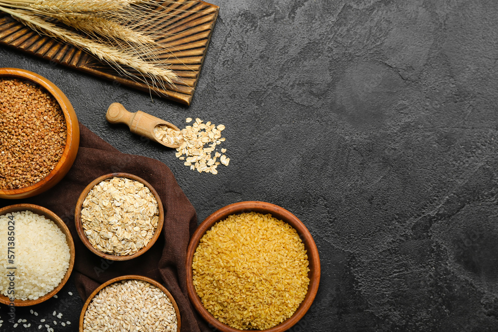 Composition with bowls of different cereals on dark background