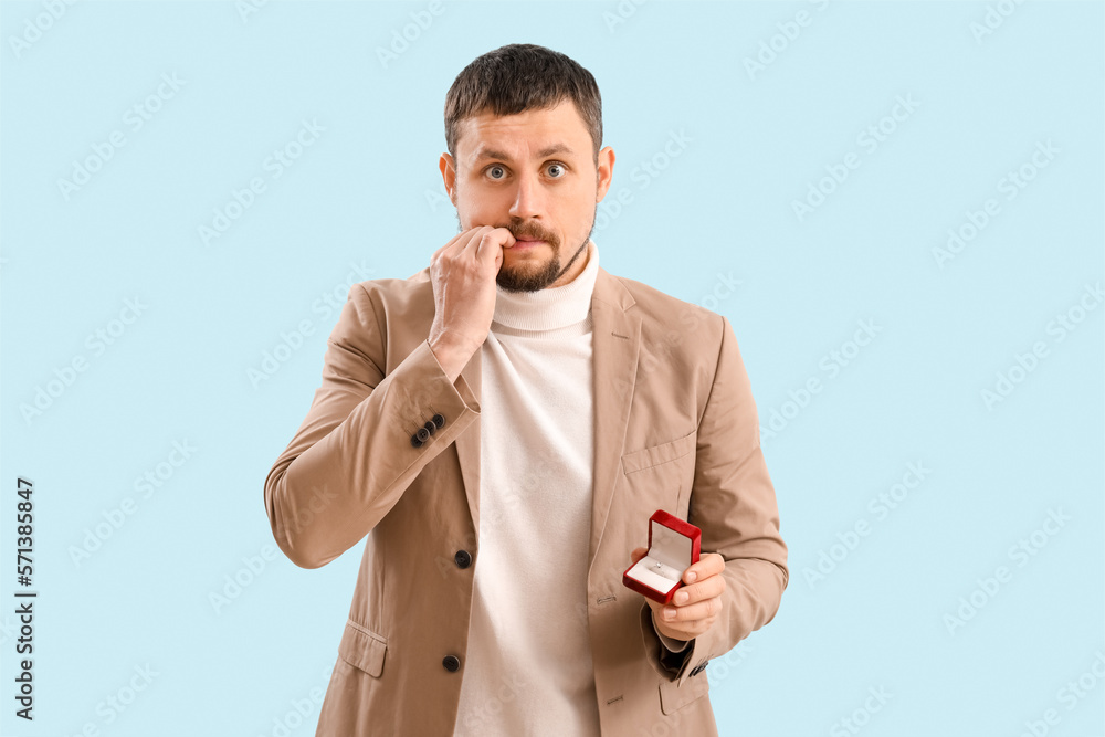 Handsome businessman biting nails on blue background