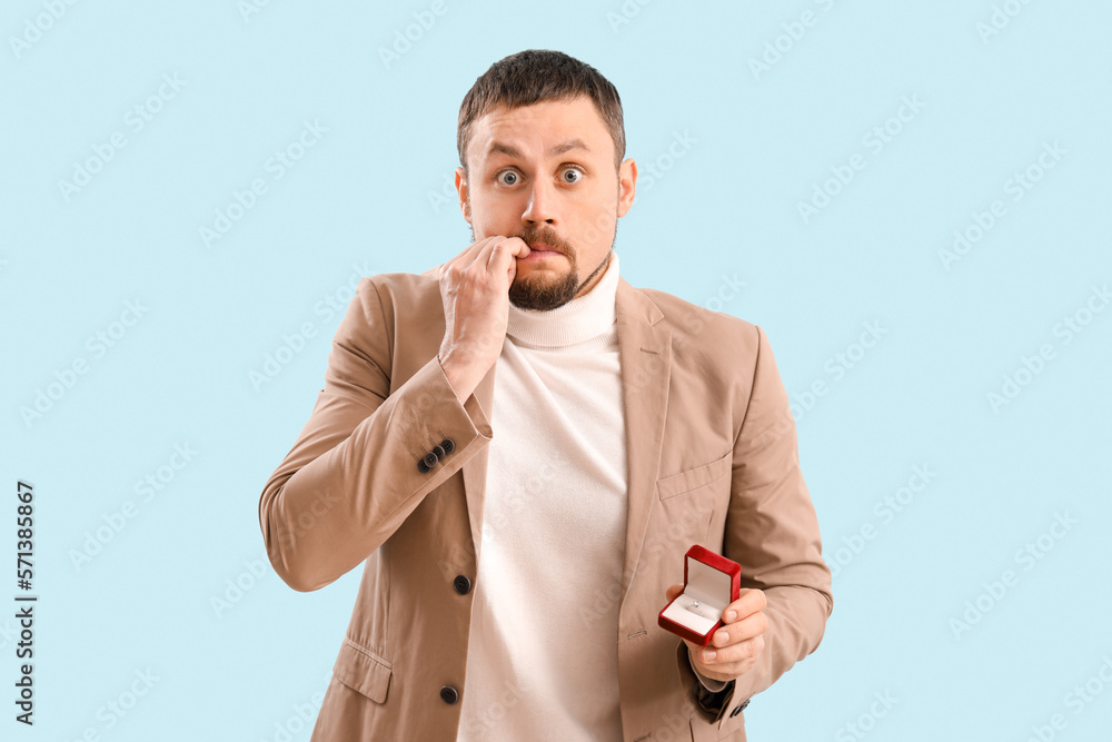 Handsome businessman biting nails on blue background