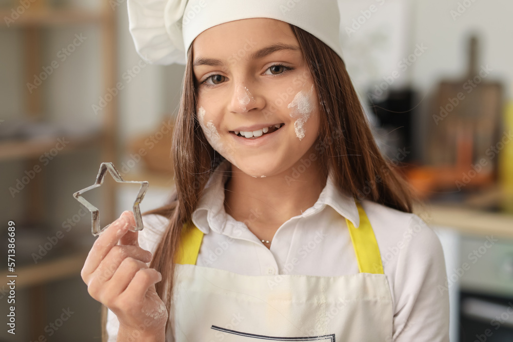 Little baker with cookie cutter in kitchen, closeup