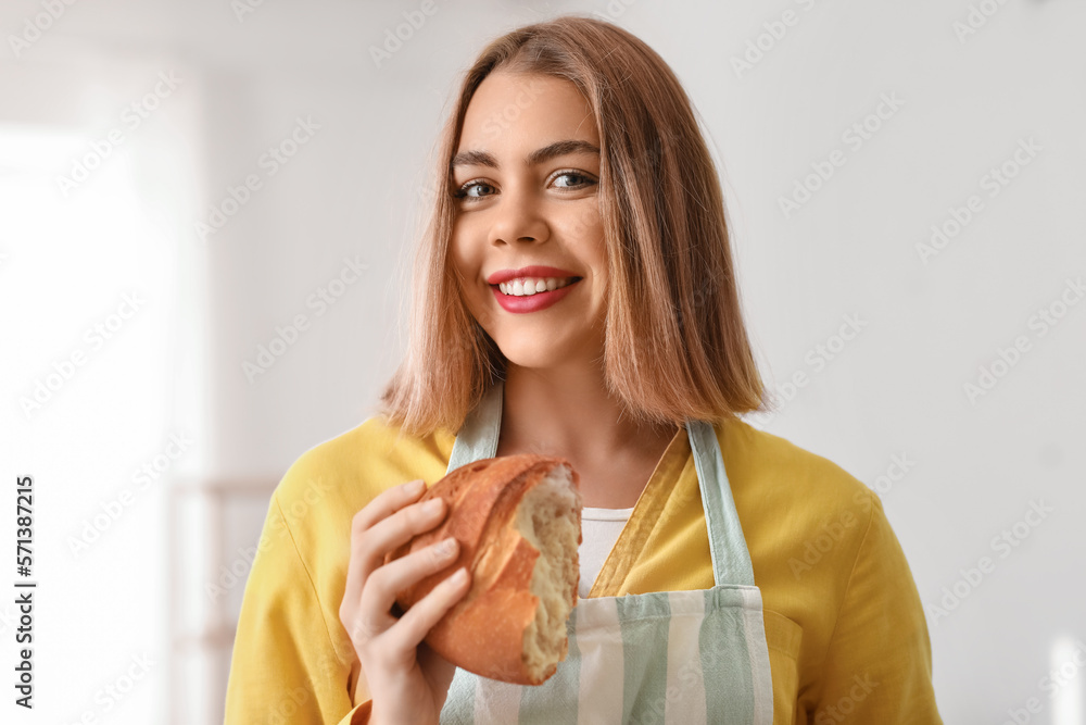 Female baker with piece of fresh bread in kitchen